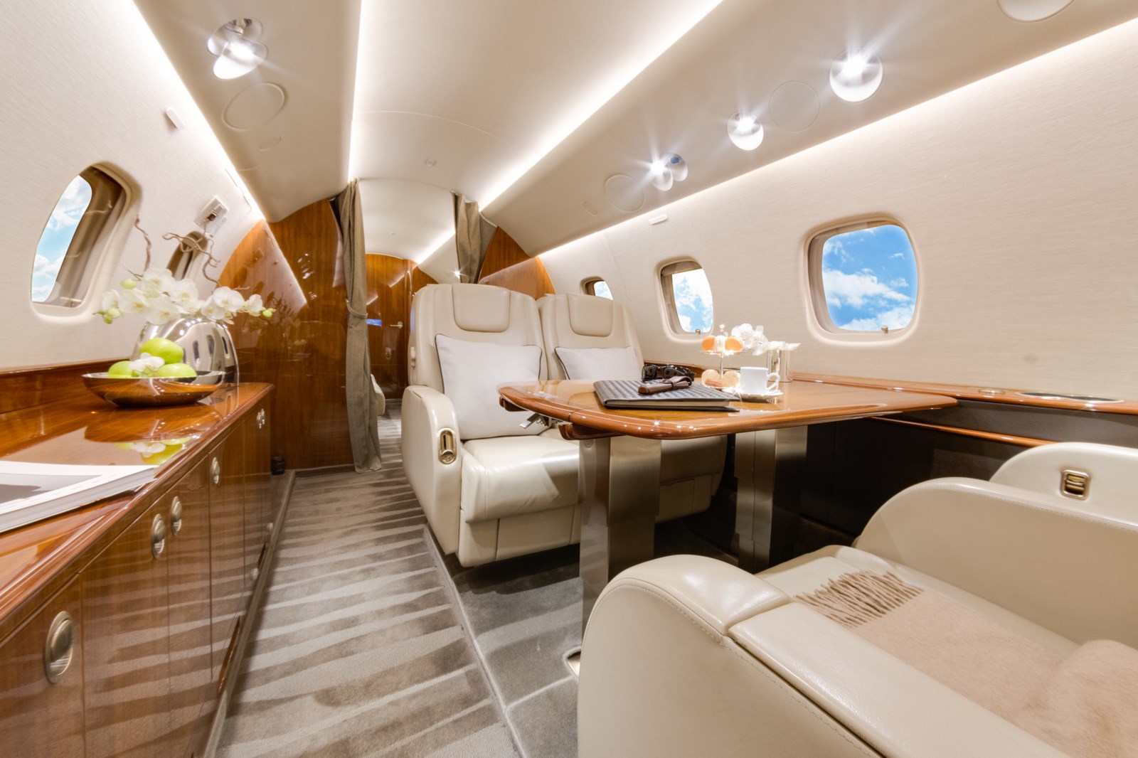 Embraer Legacy 650 cabin with cream leather seats and a dining table