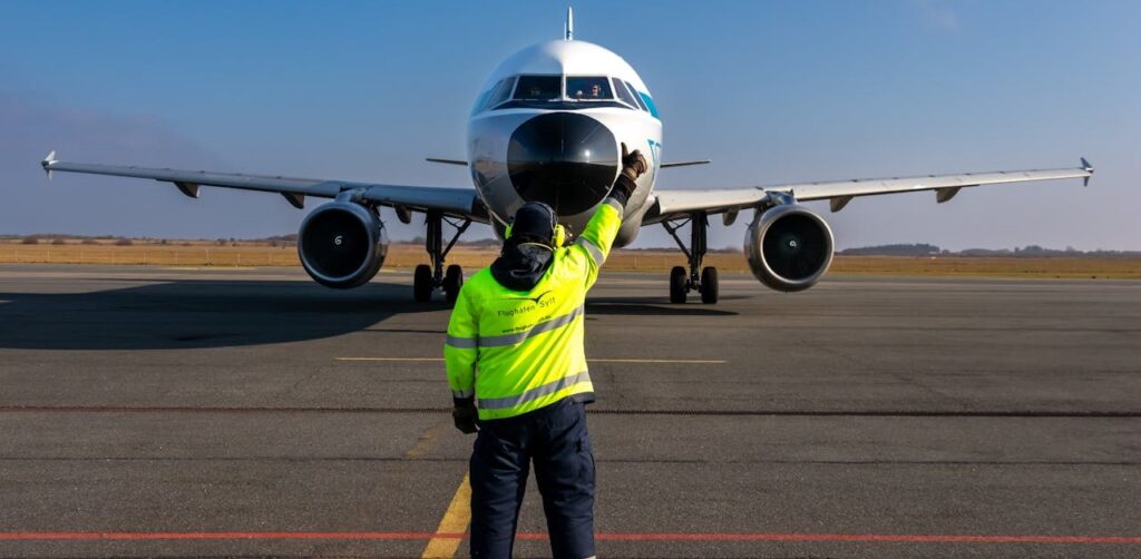 Airport worker guiding airplane on runway