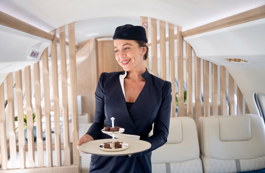 Flugbegleiterin, die Passagiere in der Kabine eines luxuriösen Privatjets bedient