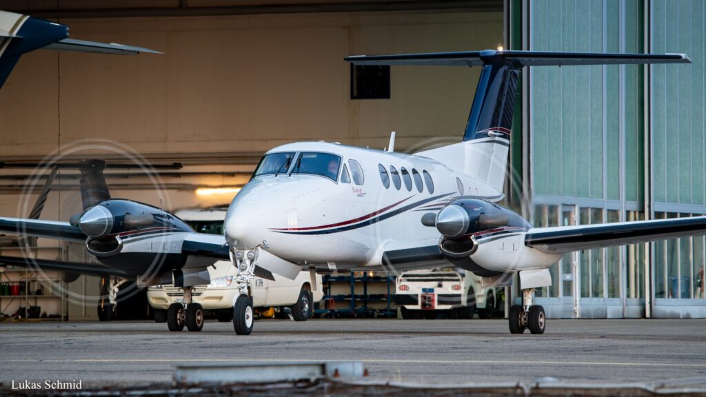 Beechcraft King Air turboprop aircraft outside a hangar, with propellers turning